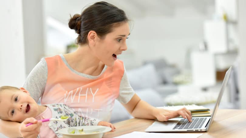 Madre ocupada tratando de alimentar al bebé y trabajar simultáneamente