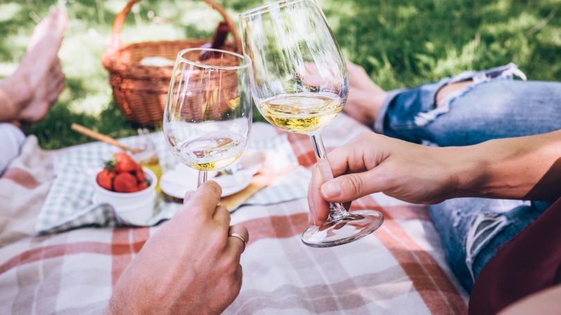 Pareja de enamorados en un picnic con vino blanco Fresas