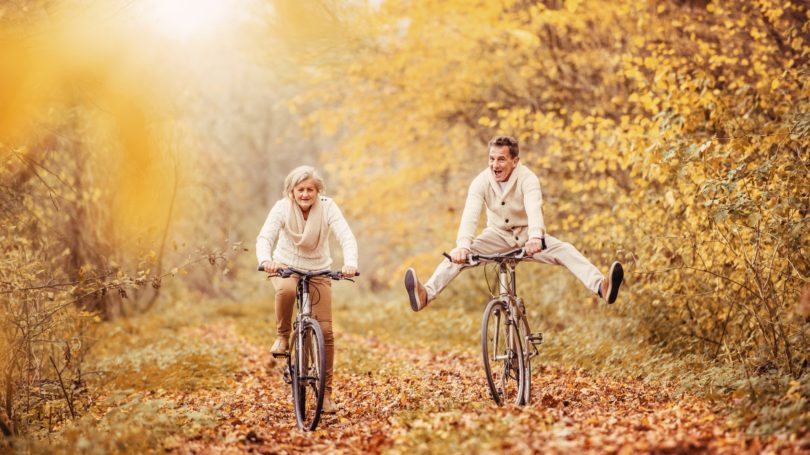 Pareja de ancianos en bicicleta a través del follaje Trail Fall