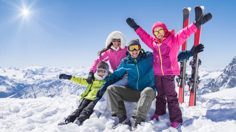 Familia disfrutando de los deportes de invierno esquiando en las montañas