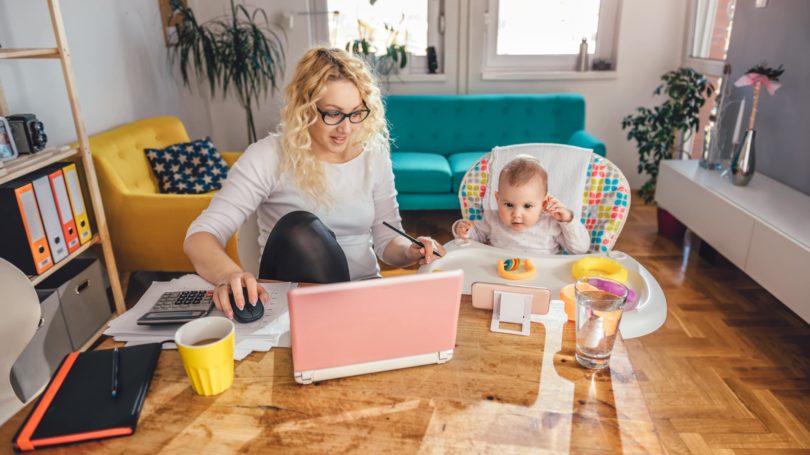 Mamá con gafas trabajando con mesa de comedor para bebés