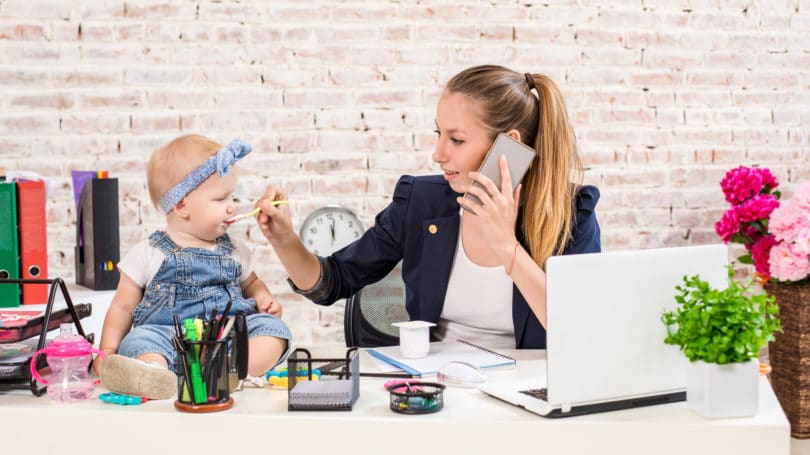 Mamá trabajando desde casa alimentando a la hija del bebé
