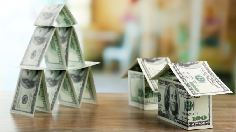 Casas de pirámides de dinero en efectivo en mesa de madera