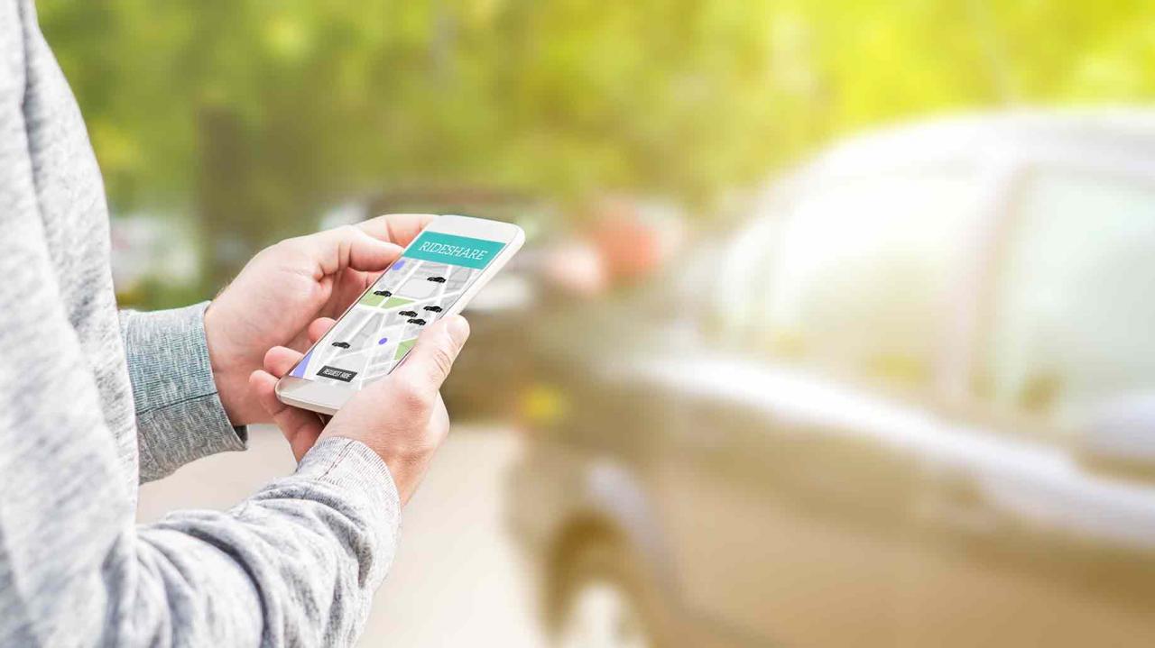 hombre que sostiene el teléfono inteligente para el servicio de transporte de aplicaciones móviles