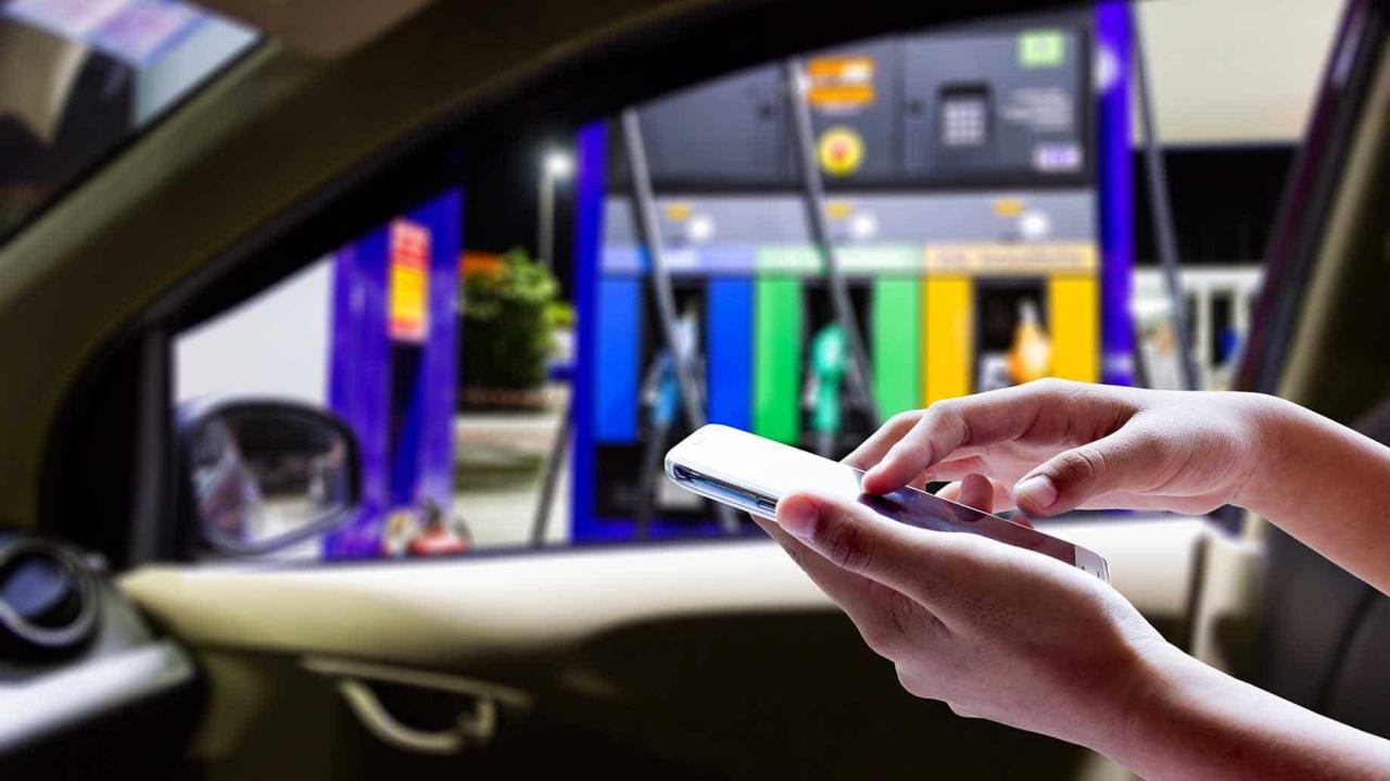 mujeres en la gasolinera con smartphone en el coche