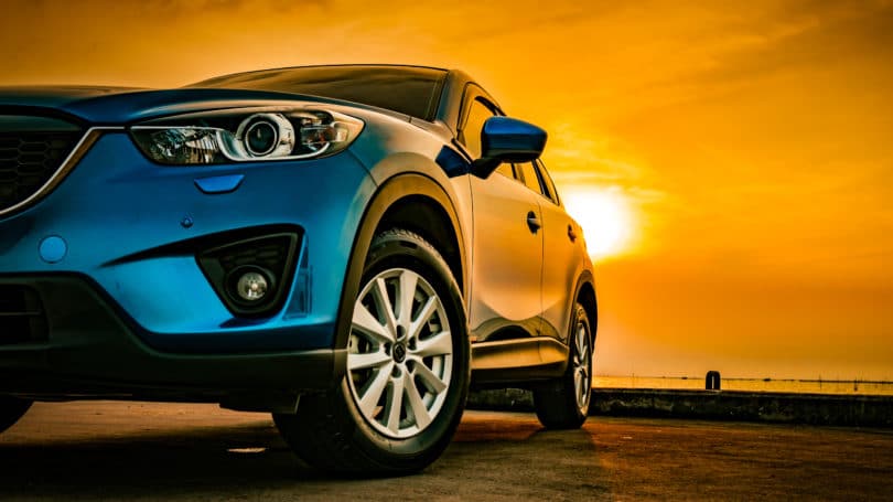 Carretera de conducción al atardecer de coche compacto azul