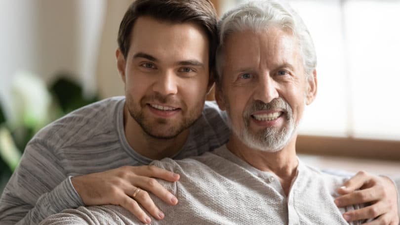 Hijo y padre anciano posando en la sala de estar