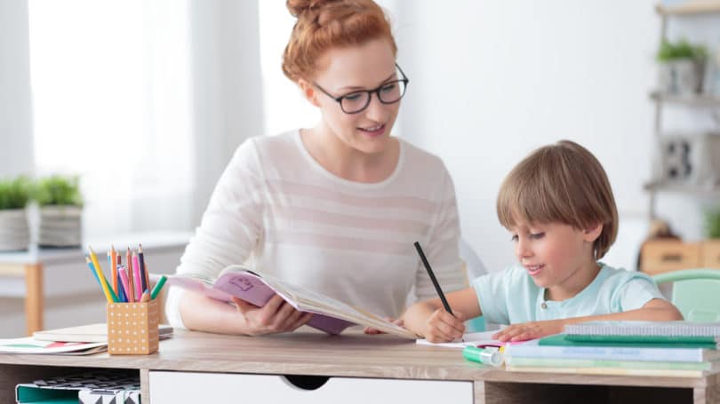 Tutor Boy ayudando con la tarea sentado en el escritorio